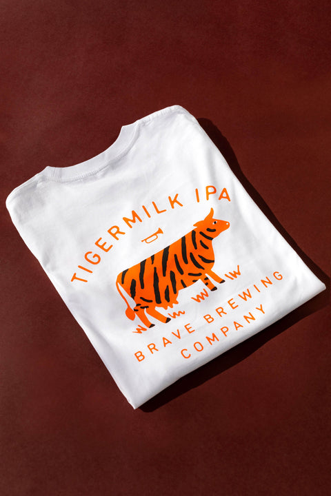 White t-shirt with orange tiger Milk Logo and text on a brown background