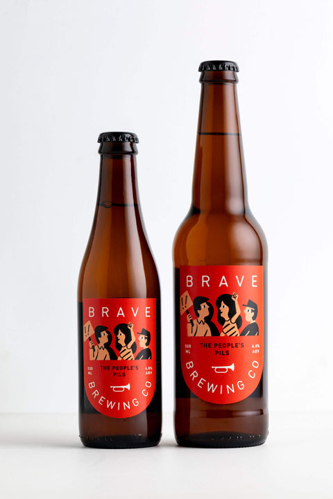 Two bottles of Brave Brewing Co. Peoples Pilsner beer on a white background