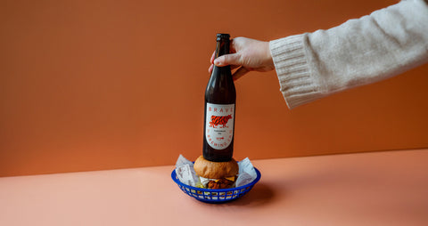 Brave Brewing homepage header, Tigermilk IPA with persons hand and burger
