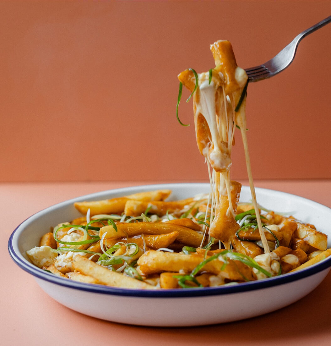 Poutine Fries with cheese stretching from a fork against an orange background