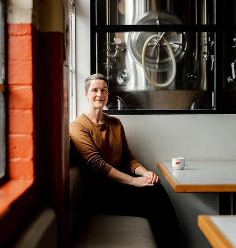 Gemma sitting at a table with a coffee cup in Brave brewing Co
