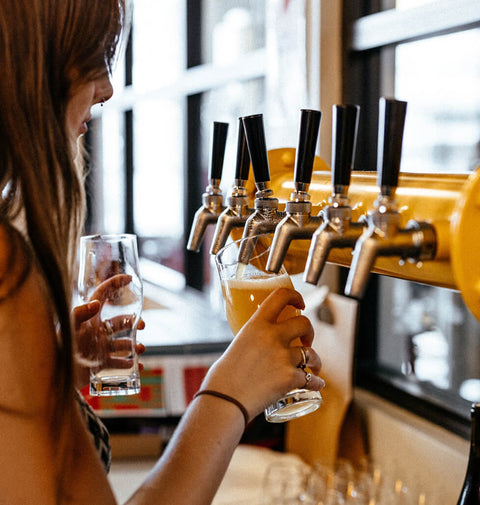 Person pouring beer from a tap into a glass at Brave brewing Co