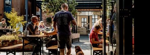 People dining outdoors in a casual setting with tables and chairs at Brave Brewing Co