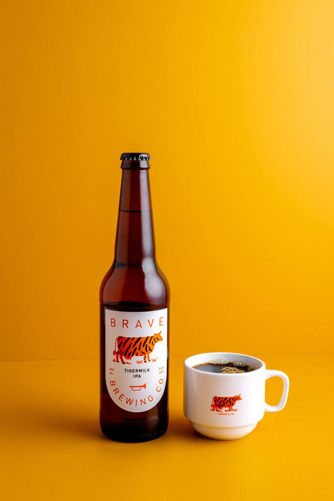 Bottle and mug of Brave Brewing Co Tiger Milk beer on a yellow background